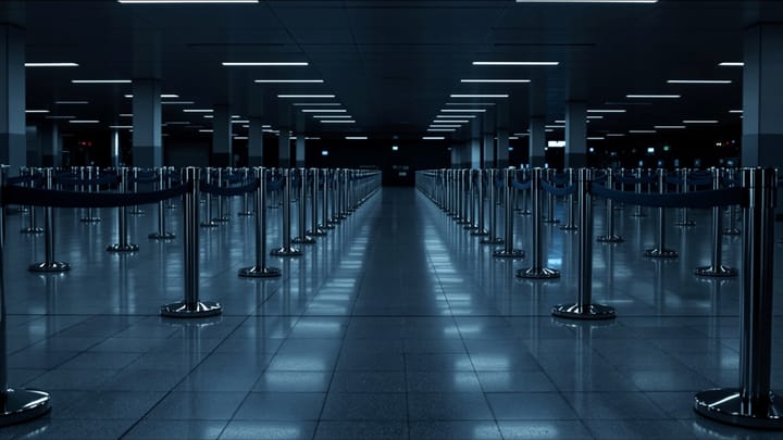 An empty maze of queue barriers in a dim immigration hall at night