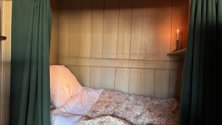 A curtained box bed with a candle in an Amsterdam hotel