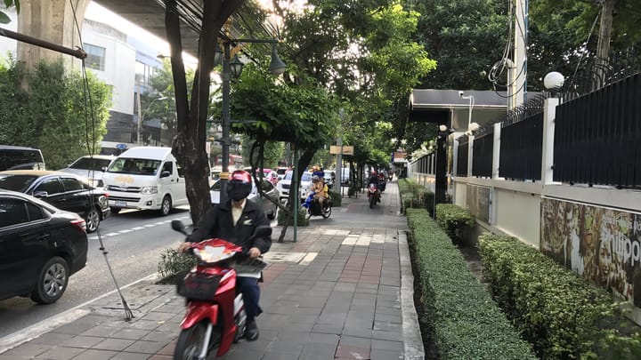A motorbike rider on a Bangkok sidewalk